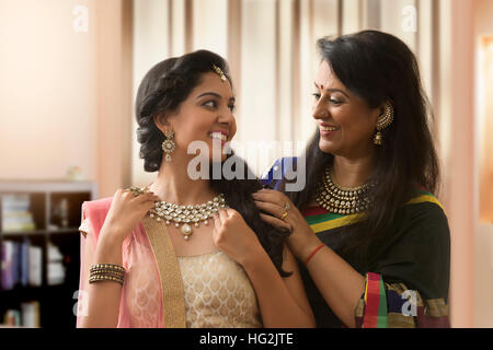 Mother helping daughter in wearing necklace Stock Photo