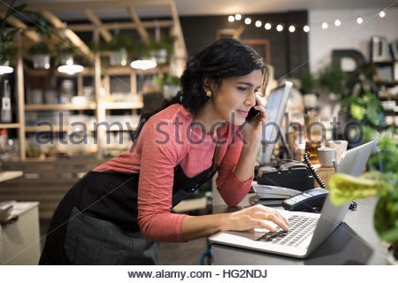 Female shop owner working at laptop at plant shop counter