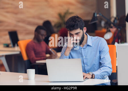 Software Developer sitting with laptop computer in startup office Stock Photo
