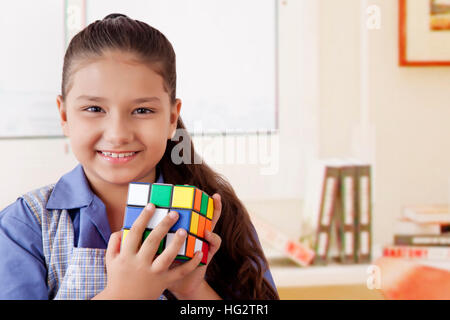 Girl in school uniform playing Rubik's cube Stock Photo