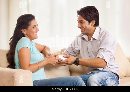 Man giving girlfriend gift on sofa Stock Photo