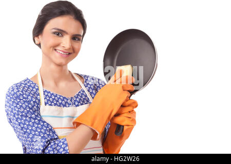 Young Indian woman holding kitchen utensil against white background Stock Photo