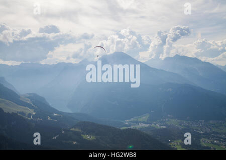 Color image of a paraglider flying, with clouds in the background. Stock Photo