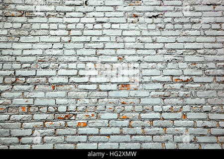 A brick wall is painted silver.  Chips of paint have peeled off revealing the original surface below. Stock Photo