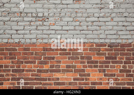 A brick wall is half natural brick and half gray painted brick. Stock Photo