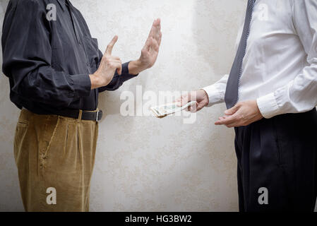 Corrupted businessman, or politician, offering a Dollars banknotes bribe to a man rejecting any kind of corruption Stock Photo