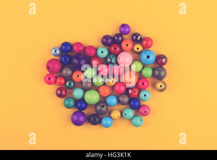 top view many colored glass pearls beads for jewelry on yellow background Stock Photo