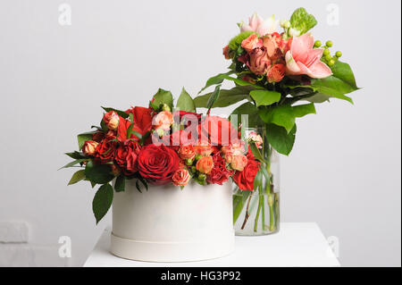 flower arrangement on table. Bouquet of roses in a paper box. vase in the background. Stock Photo