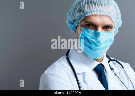 Handsome doctor wearing face mask and surgical scrub cap Stock Photo
