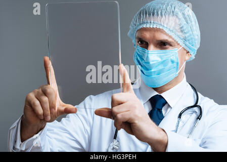 Handsome doctor in face mask posing with medical glass Stock Photo