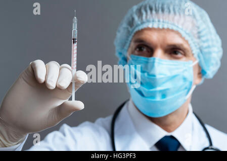 Handsome doctor holding hypodermic needle Stock Photo