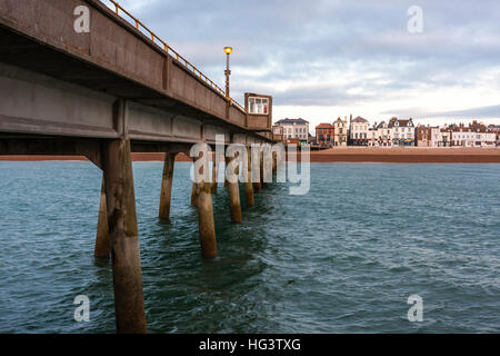 Deal Pier, in Kent England. Concrete pier build in the 1950s. View from end of pier looking back to beach and town. Dawn dark clouds in sky. Calm sea. Stock Photo