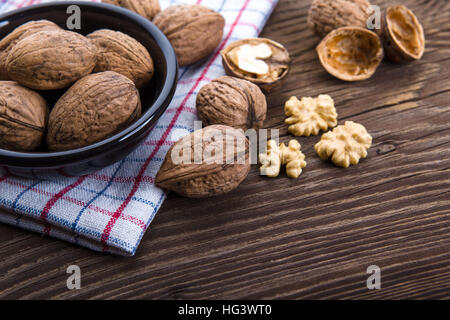 Walnut kernels and whole walnuts on old wooden table Stock Photo