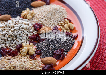 Assortment of fresh dried seeds Used as ingredients in cooking. Sunflower, sesame, linseed, poppy, chia, nuts, rolled oats and Cranberries on plate. Stock Photo