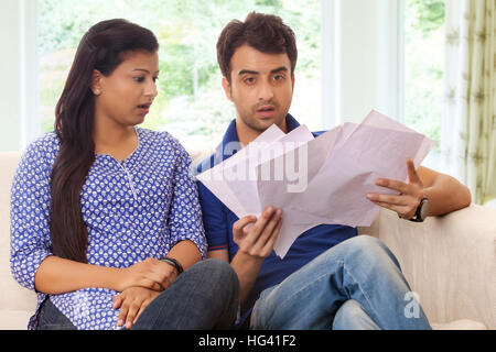 Couple surprised looking at bills Stock Photo