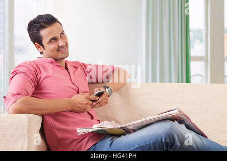 Young man thinking while using phone Stock Photo