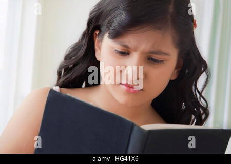 Portrait of angry girl reading book Stock Photo