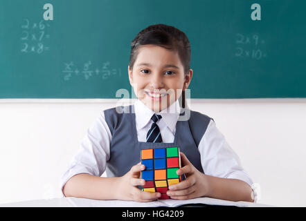 Girl with Rubik cube in a classroom Stock Photo