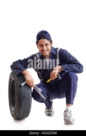 Portrait of car mechanic with spare tyre and hand tools Stock Photo