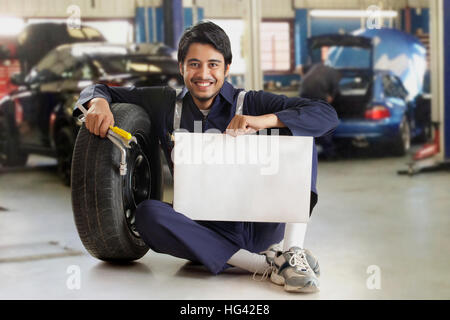 Car mechanic holding blank card in garage Stock Photo