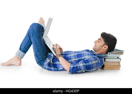 Happy Indian man lying on floor using a laptop PC Stock Photo
