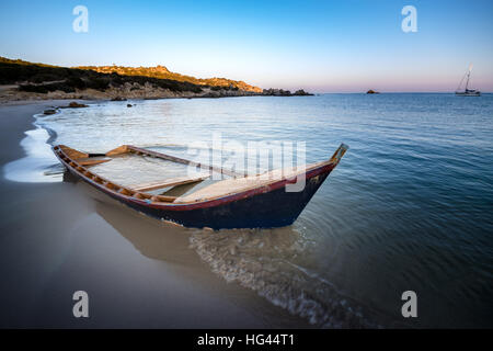Old wooden boat wrecked on a sandy beach.
