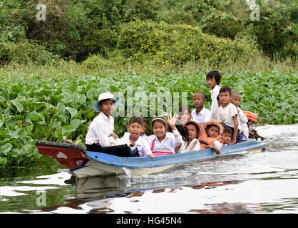 Little boat with school children  Floating Village The Sangkhae - Sangker River Battambang Province Cambodia.The Tonle Sap fresh water lake ( richest fishing lake in the World ) drains into the Mekong River at Phnom Penh. The local Cambodian population has also adapted to the unique ecology of the lake with floating ( fishermen -fishery ) villages and stilted houses. Stock Photo