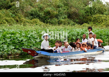 Little boat with school children  Floating Village The Sangkhae - Sangker River Battambang Province Cambodia.The Tonle Sap fresh water lake ( richest fishing lake in the World ) drains into the Mekong River at Phnom Penh. The local Cambodian population has also adapted to the unique ecology of the lake with floating ( fishermen -fishery ) villages and stilted houses. Stock Photo