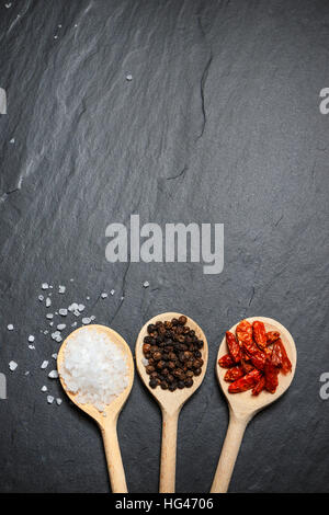 spices in wooden spoons over black stone background, top view with copy space Stock Photo