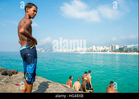 RIO DE JANEIRO - JANUARY 19, 2015: Young Brazilians gather at the rocky point of Arpoador to jump in the sea. Stock Photo