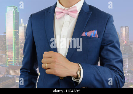Man in blue suit with pink bow tie, flower brooch, and pink blue strip pocket square, close up Stock Photo