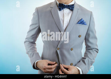 Man in grey suit, plaid texture, blue bowtie and pocket square, close up white background Stock Photo