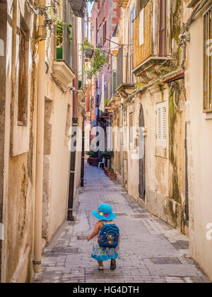 Little girl heading down a narrow Sicilian lane, Syracuse, Sicily, Italy Stock Photo
