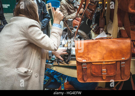 Woman manufacturing purses and leather handbags directly on the street hot print with a kwik-print stamp machine Stock Photo