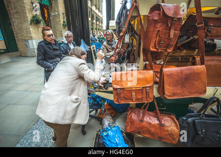 Woman manufacturing purses and leather handbags directly on the street hot print with a kwik-print stamp machine Stock Photo
