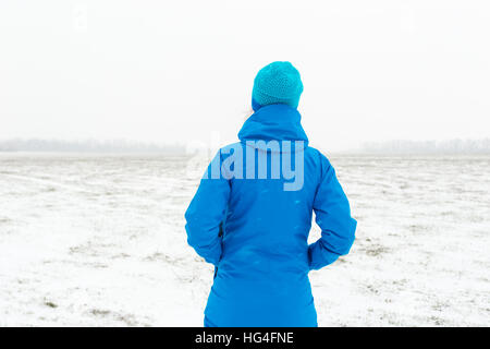 Woman in blue standing in a snowy field Stock Photo