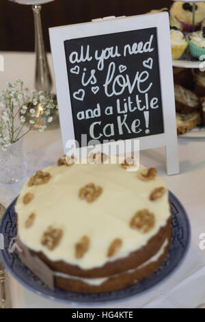 Wedding celebration afternoon tea set out on blue and white porcelain with handwritten blackboard sign and tiered cake stand Stock Photo