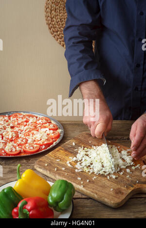 Man knife sliced onion pizza on a cutting board vertical Stock Photo