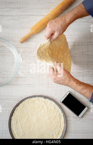Man cooking dough for two pizzas on the table vertical Stock Photo