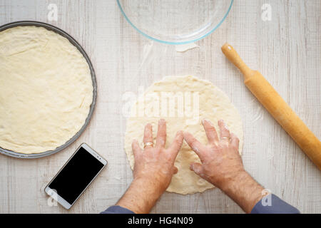 Man cooking dough for two pizzas on the wooden table horizontal Stock Photo