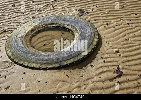 Old Tyre Discarded on Beach Stock Photo