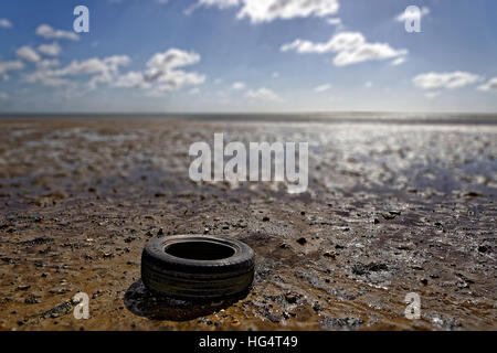 Old Tyre Discarded on Beach Stock Photo