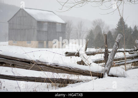 An ontario bank barn with split cedar rail fence in the snow in winter Stock Photo