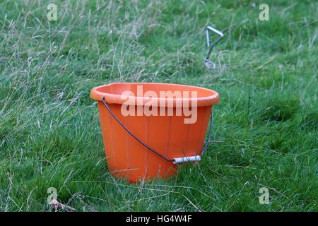 A plastic orange bucket on grass Stock Photo