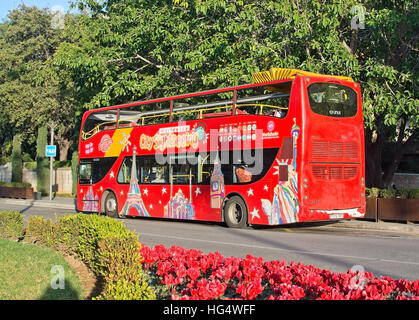 Red tourist sightseeing bus and red flowers in the city in Palma de Mallorca, Spain Stock Photo