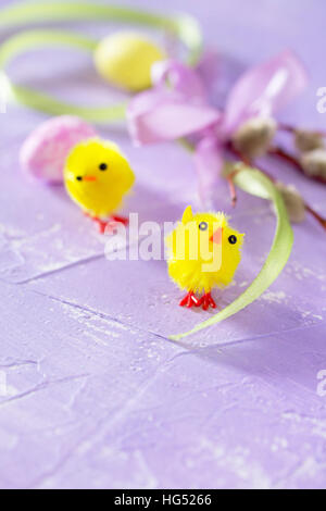 Colorful Easter frame - quail eggs, chickens and willow branch on a lilac background concrete. Stock Photo