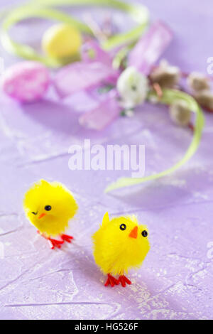 Colorful Easter frame - quail eggs, chickens and willow branch on a lilac background concrete. Stock Photo