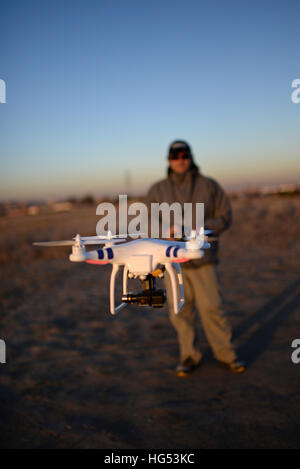 Young man flying a quadcopter DJI phantom drone outdoors Stock Photo