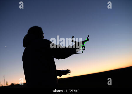 Young man flying Phantom Drone outdoors at sunset Stock Photo