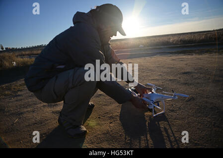 Young man flying a quadcopter DJI phantom drone outdoors Stock Photo